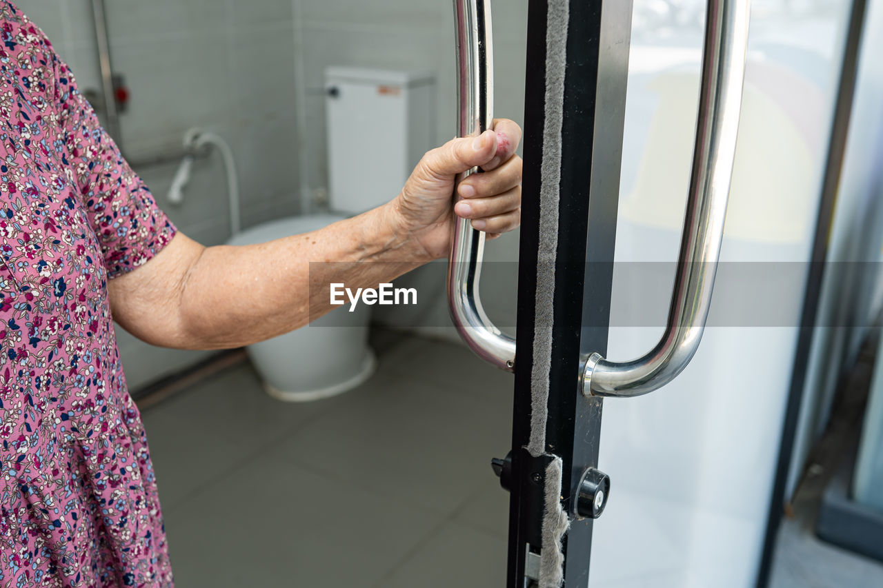 Midsection of senior woman holding door