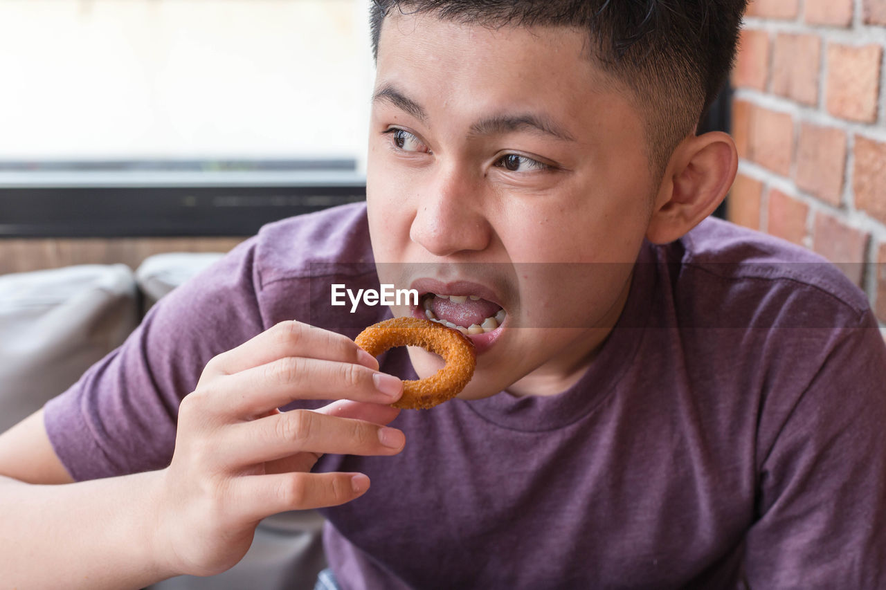 Young boy eating fried onions.