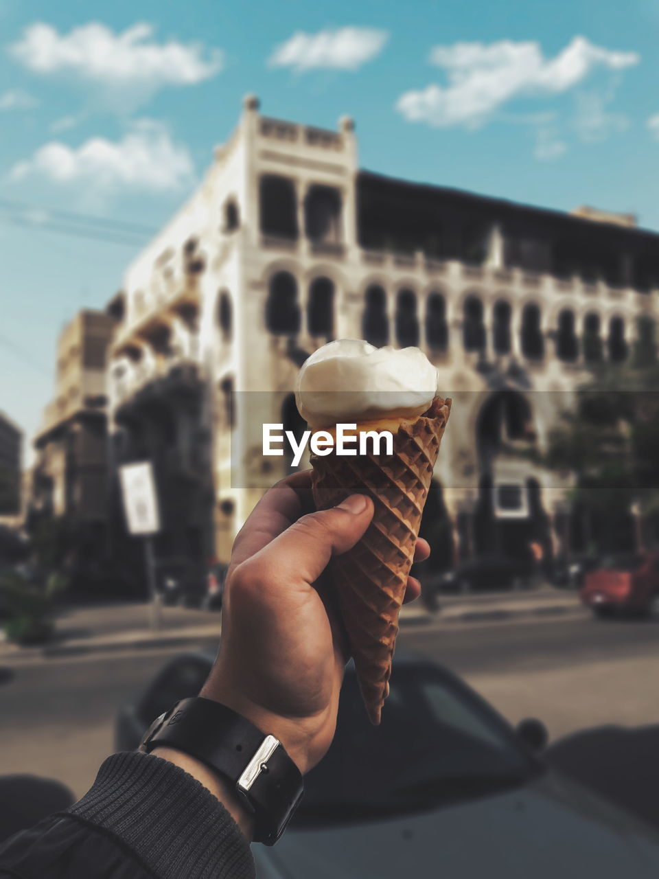 Cropped hand of man having ice cream cone in city