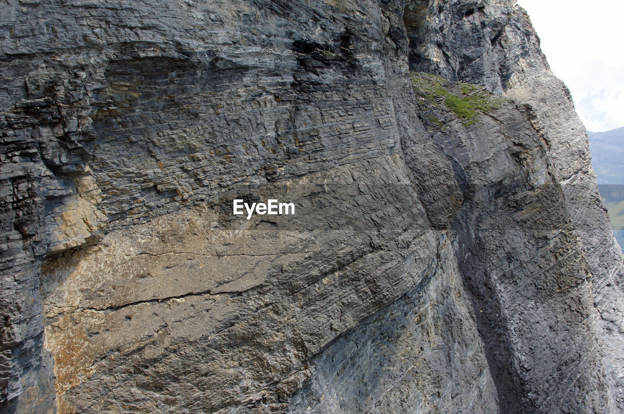 CLOSE-UP OF ROCK ON WALL AGAINST SKY