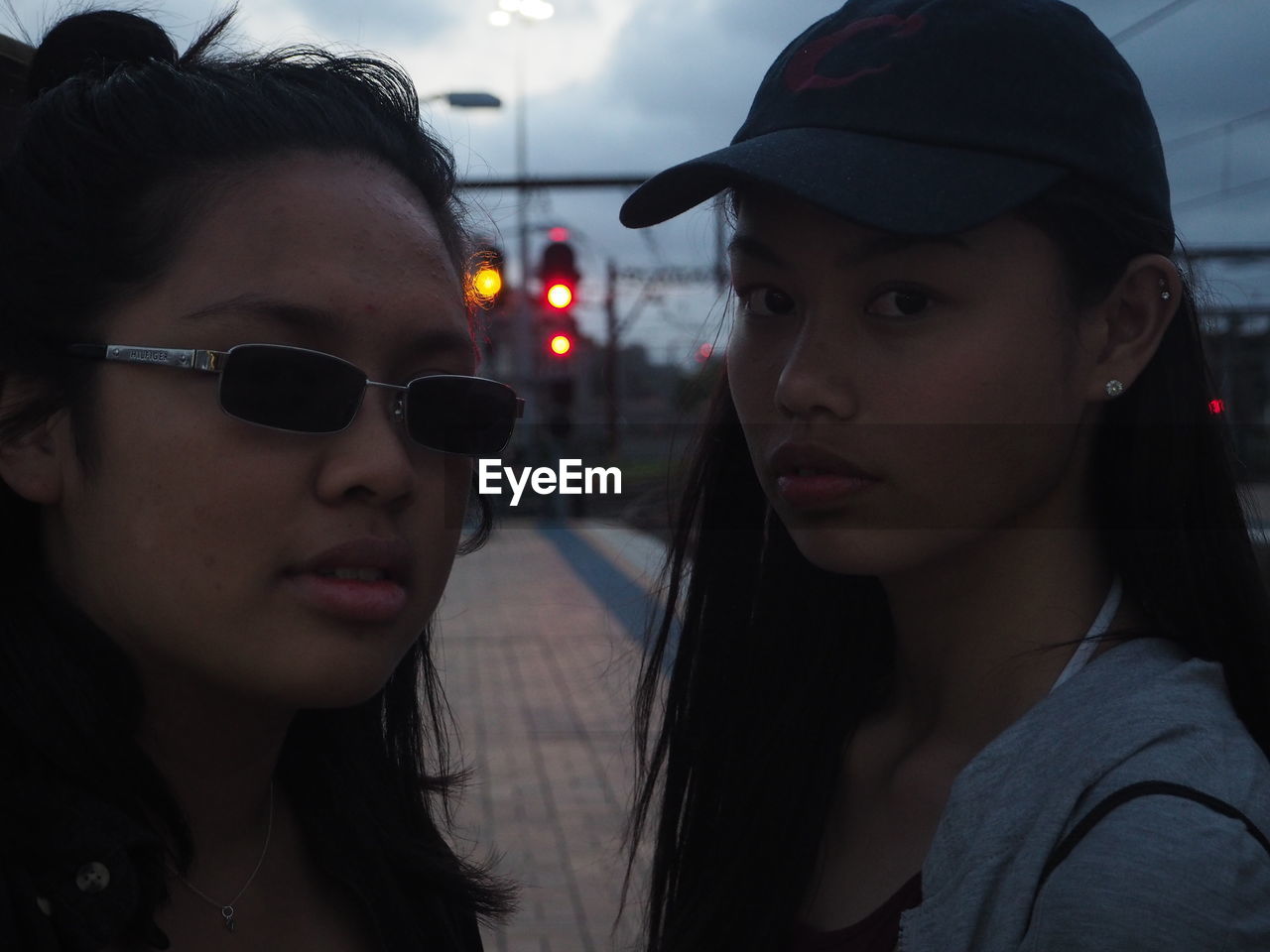 Portrait of friends standing on railroad station platform at dusk