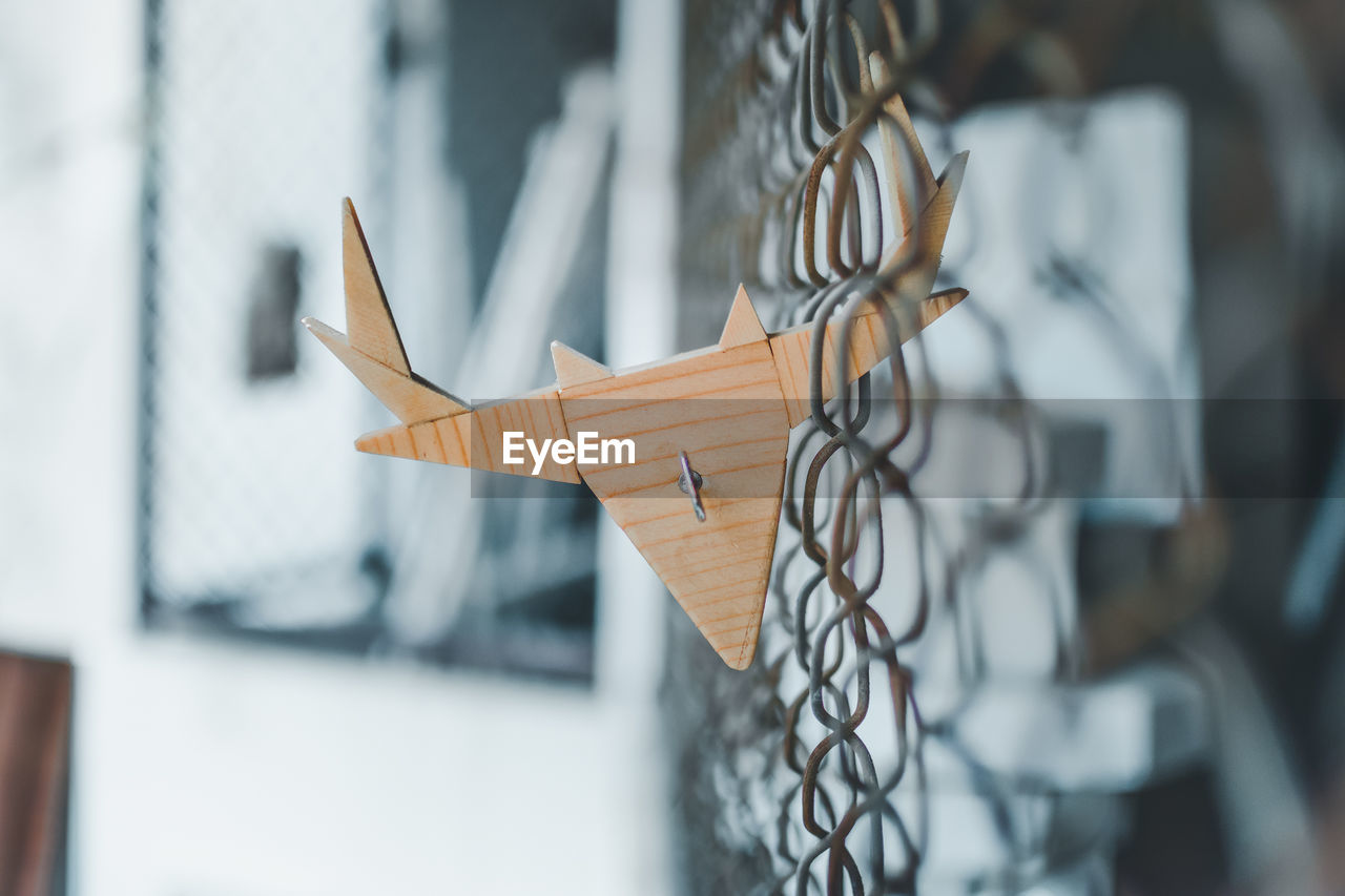 Close-up of animal shape wood hanging on metal fence