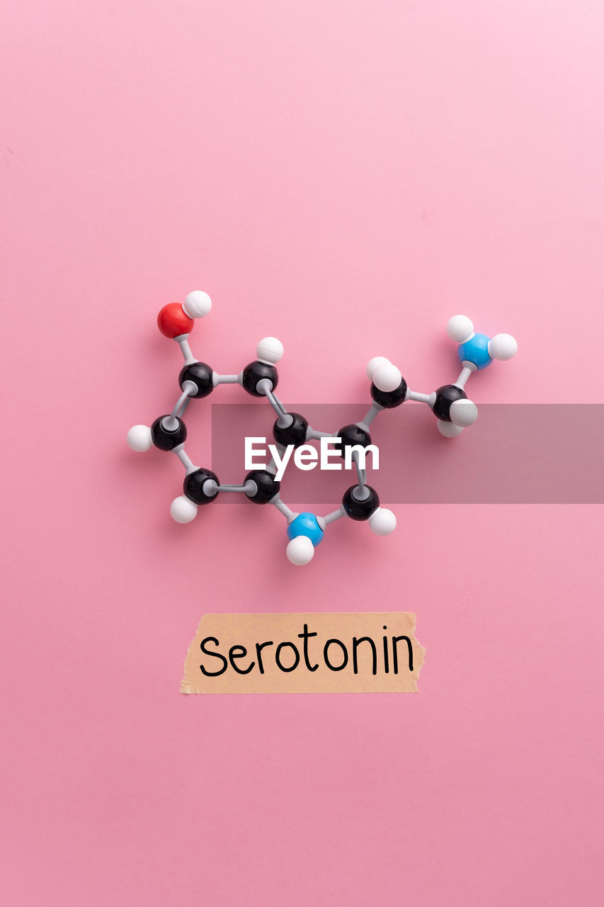Glucose sugar molecule and serotonin text against pink background