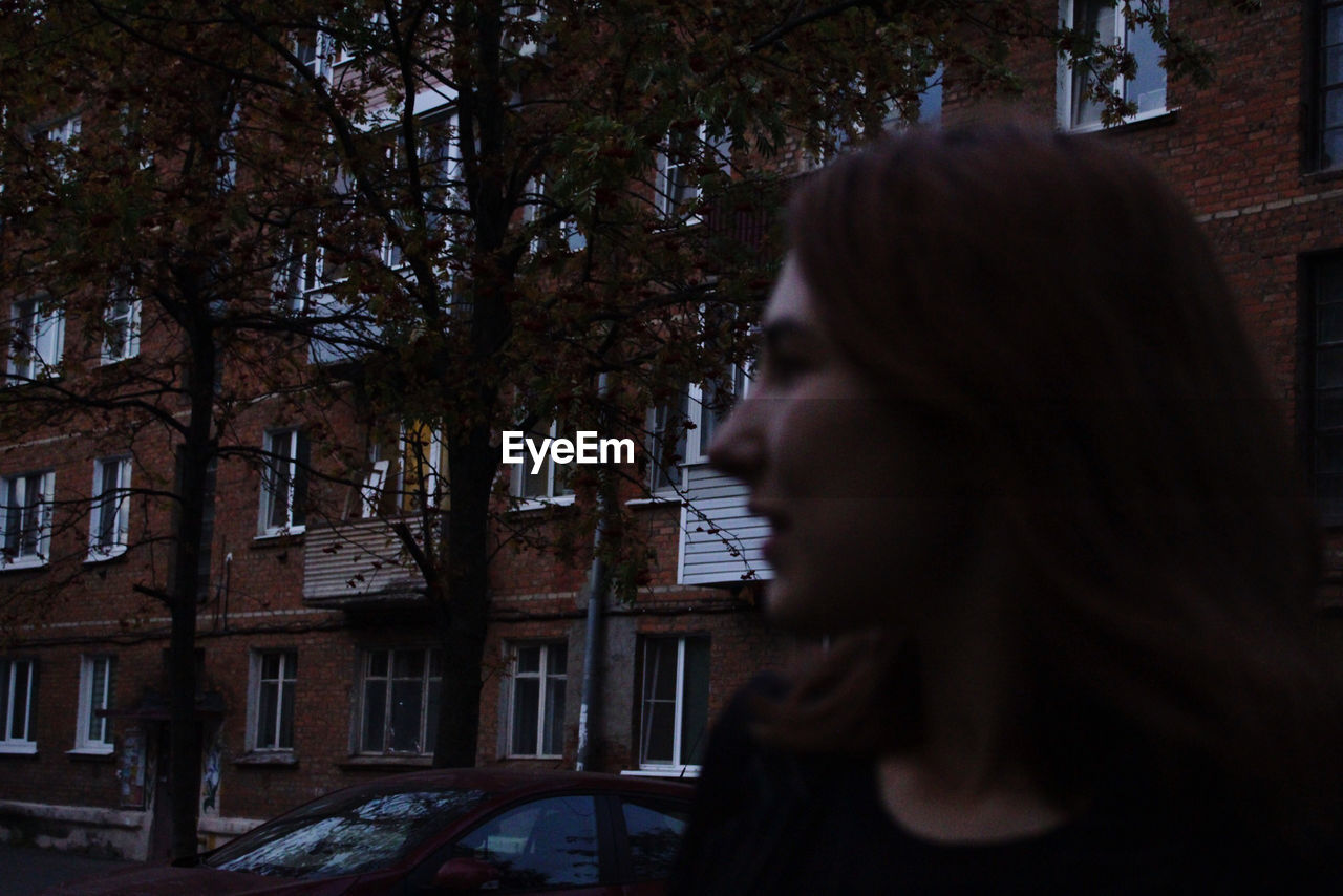 PORTRAIT OF YOUNG WOMAN LOOKING AT TREE