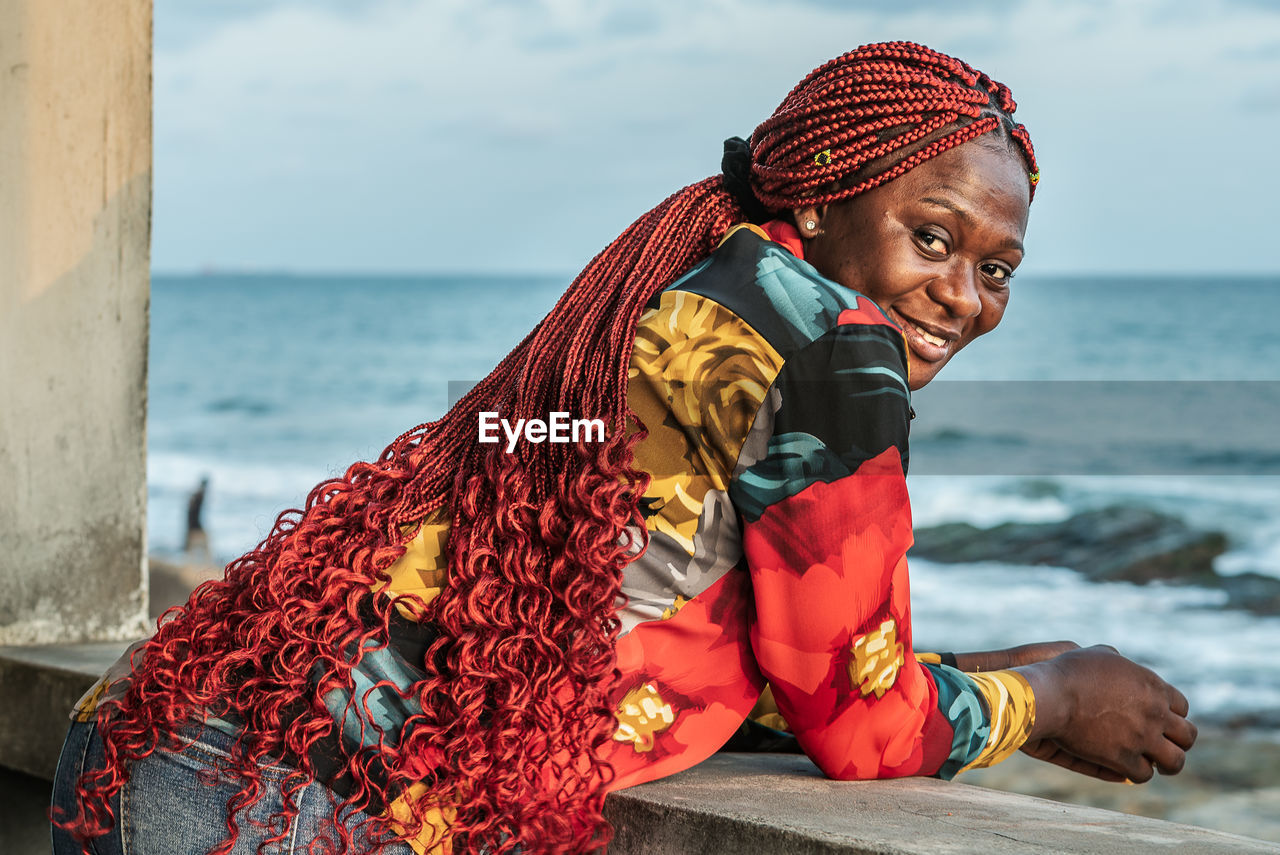 African woman with beautiful red rasta hair looking out over the sea from a balcony in accra ghana