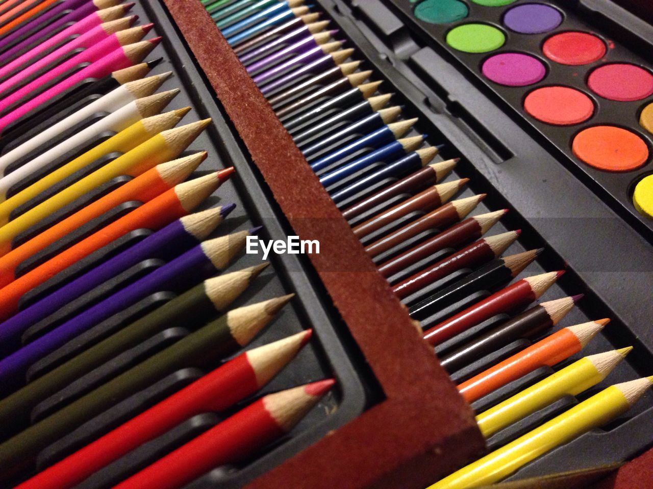 High angle view of colored pencils and watercolor palette