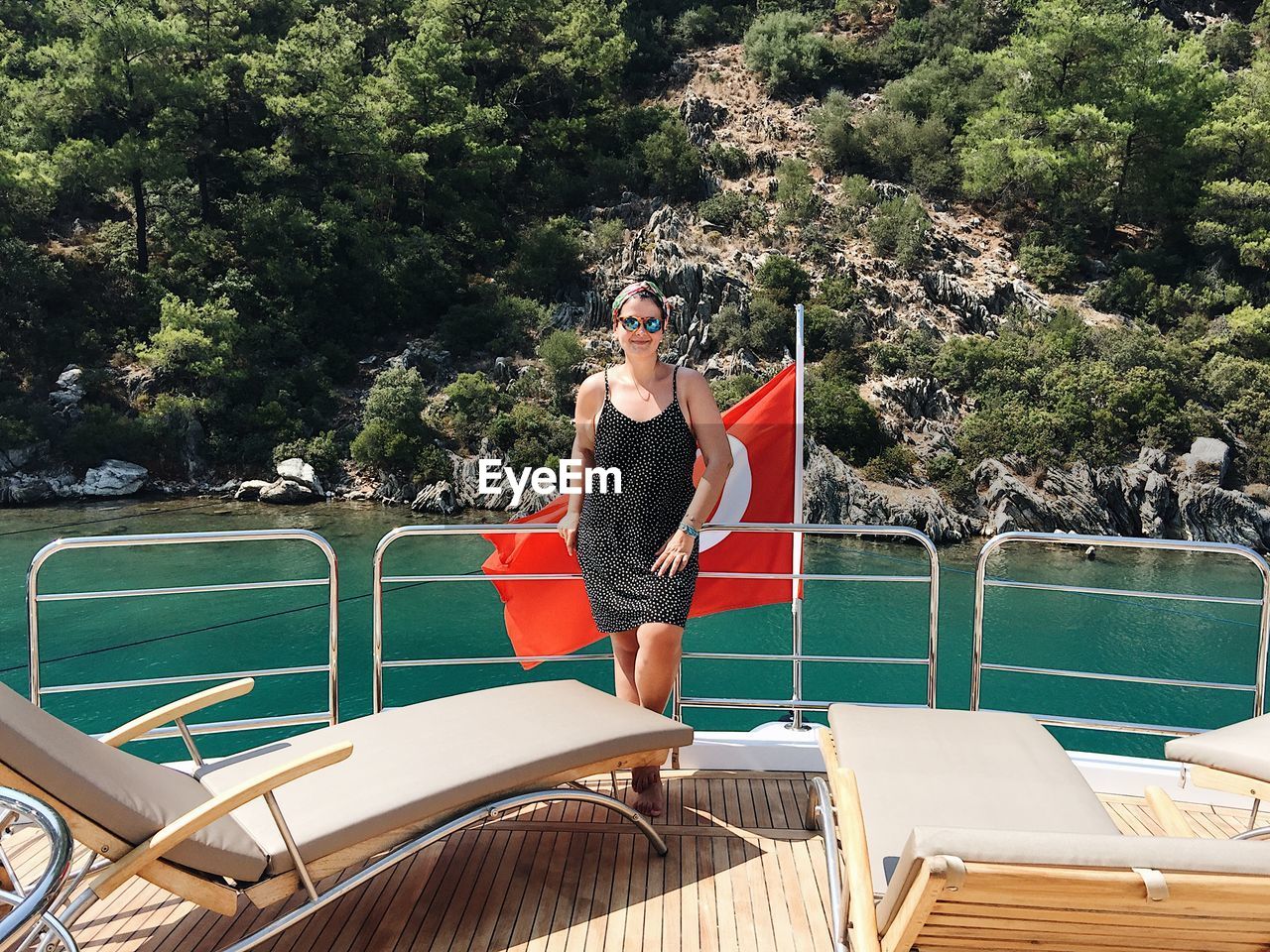 Woman standing by turkish flag in boat on sea