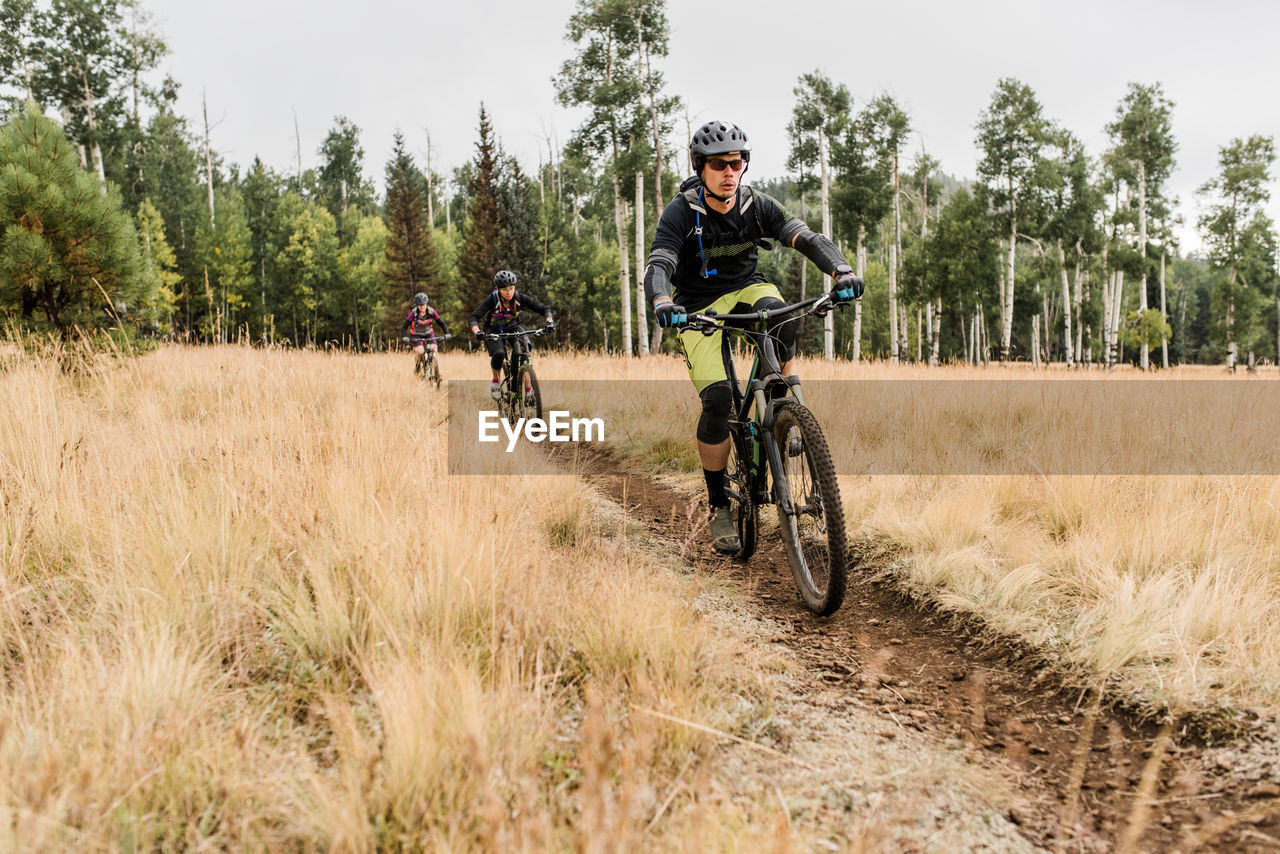 Friends riding mountain bikes on meadow trail