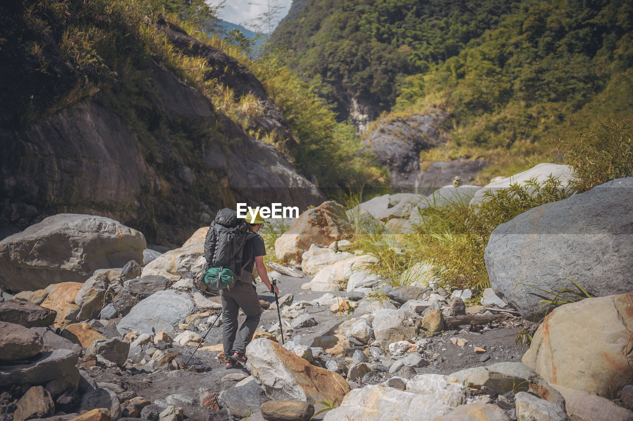 MAN ON ROCKS BY MOUNTAINS