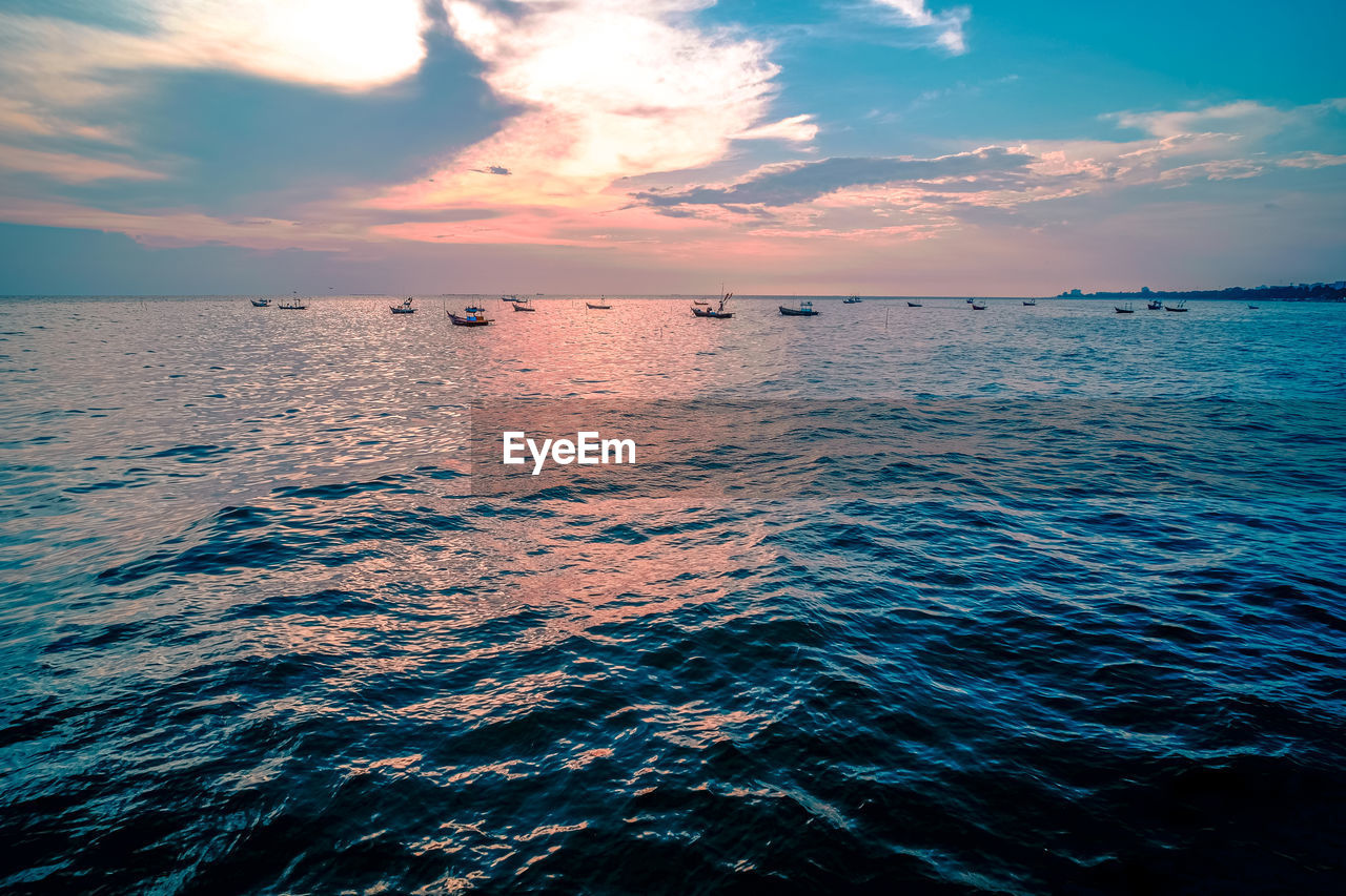 Beautiful sunrise on sea background with tropical wooden fishing boat