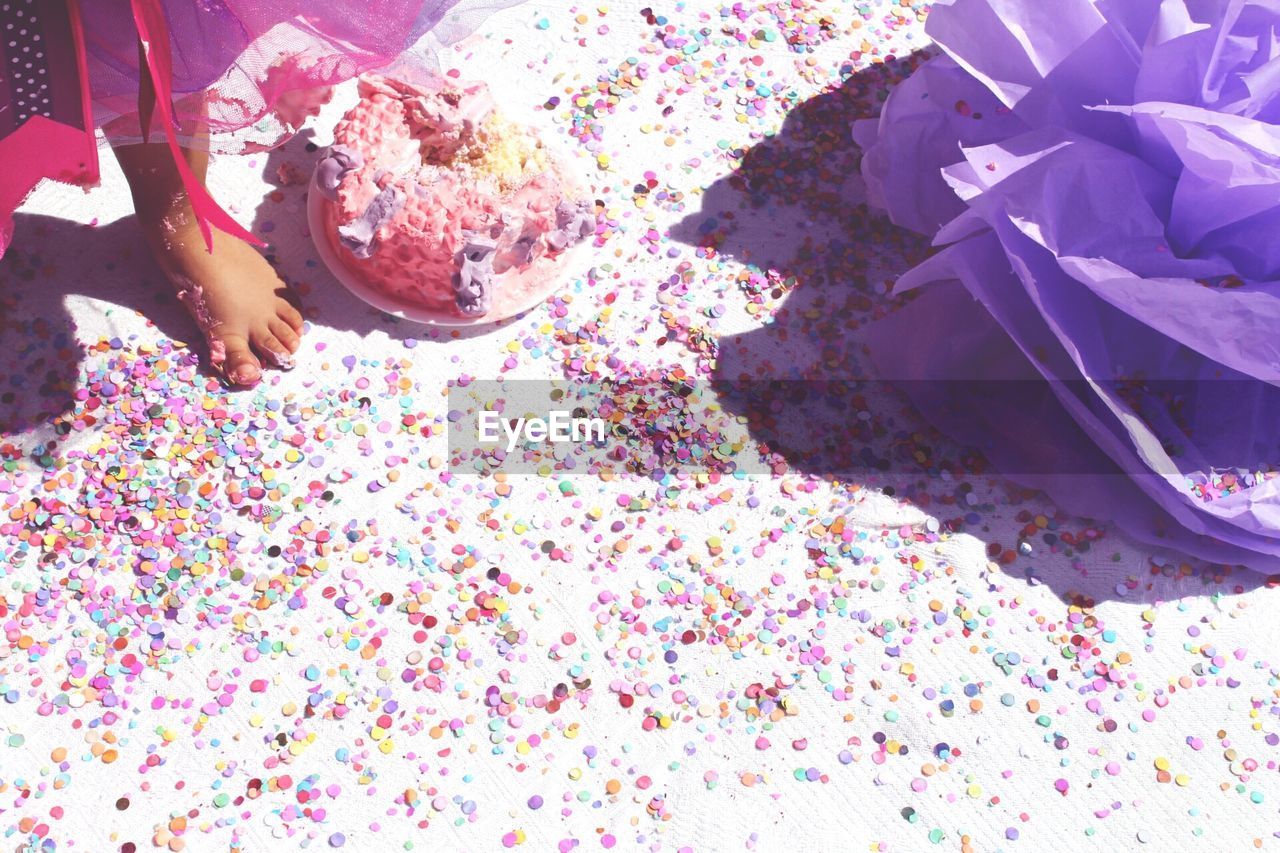 Low section of girl standing by messy birthday cake on floor