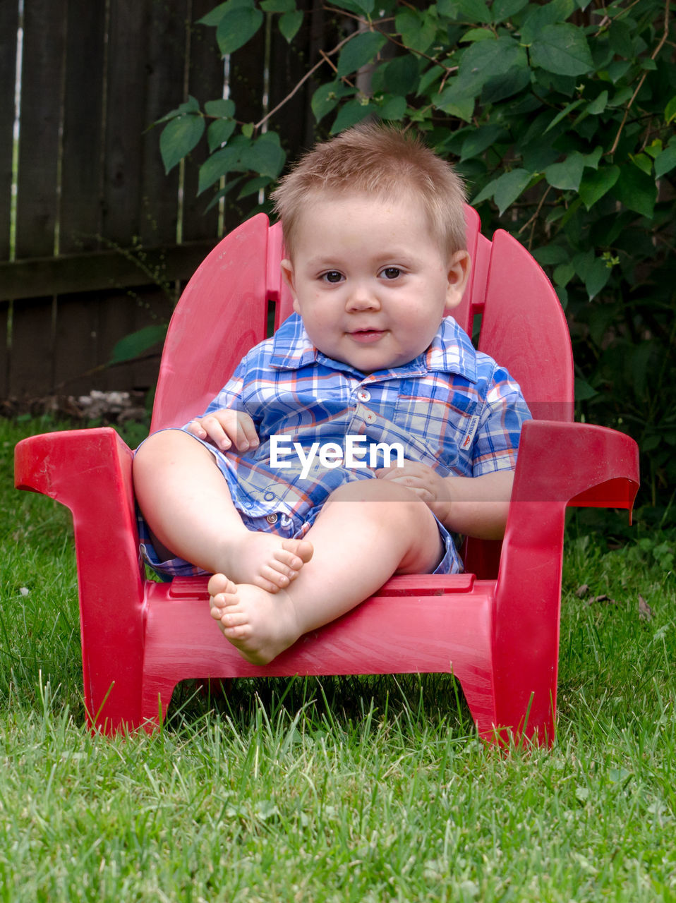 Young boy in red chair poses happily