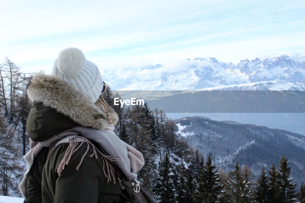 Woman in warm clothing against snowy mountains