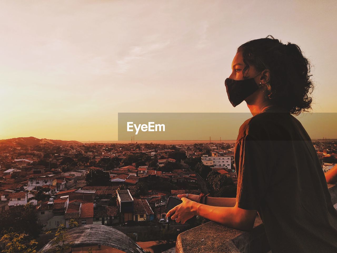 SIDE VIEW OF YOUNG WOMAN LOOKING AT CITY BUILDINGS