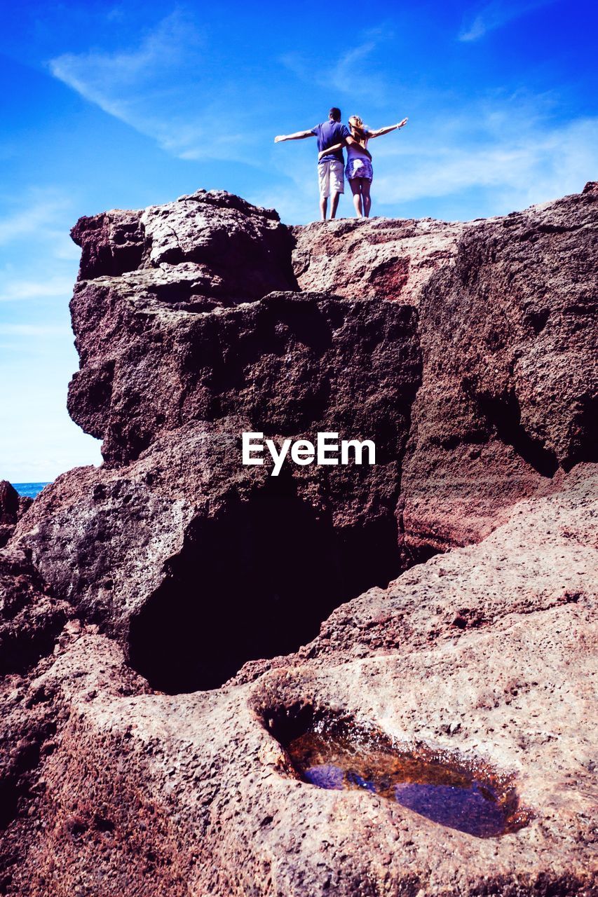 Rear view of man and woman standing on cliff