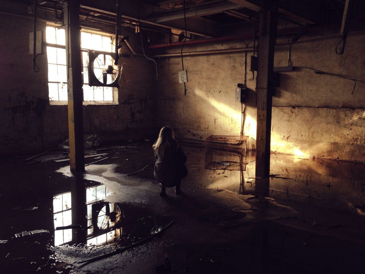 Woman crouching on wet abandoned building