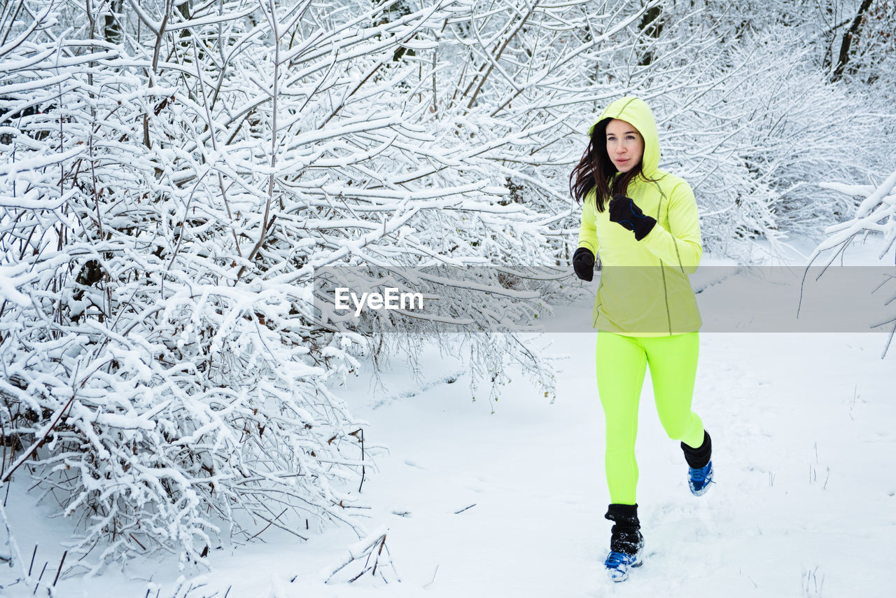 Cold weather running. happy woman running in winter snowy park, forest. running athlete woman