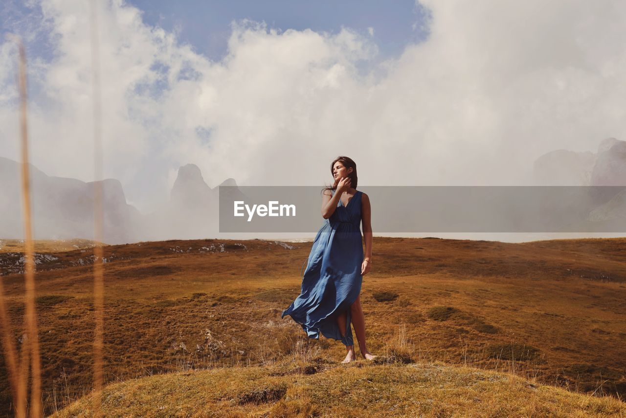 Full length of woman standing on landscape against sky