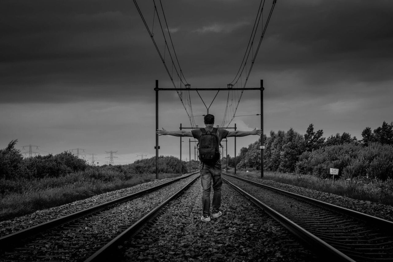 RAILROAD TRACKS AGAINST CLOUDY SKY