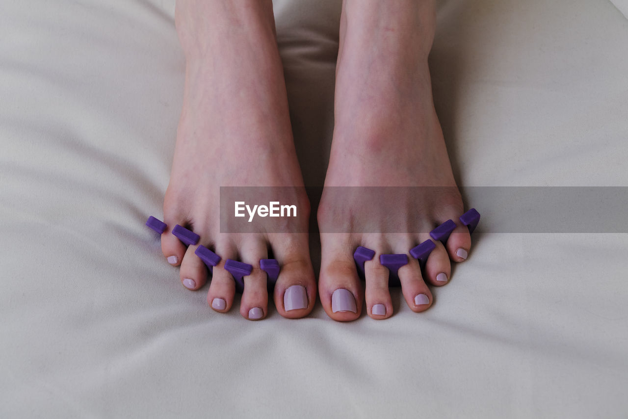 Close-up of female feet painted grey nail polish, self made pedicure at home.