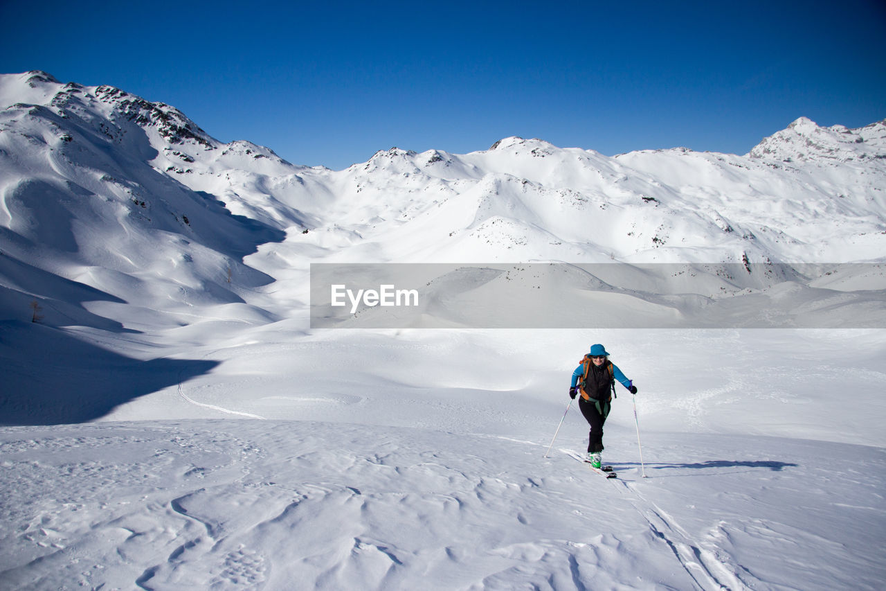 Woman skiing on snowcapped mountain against sky