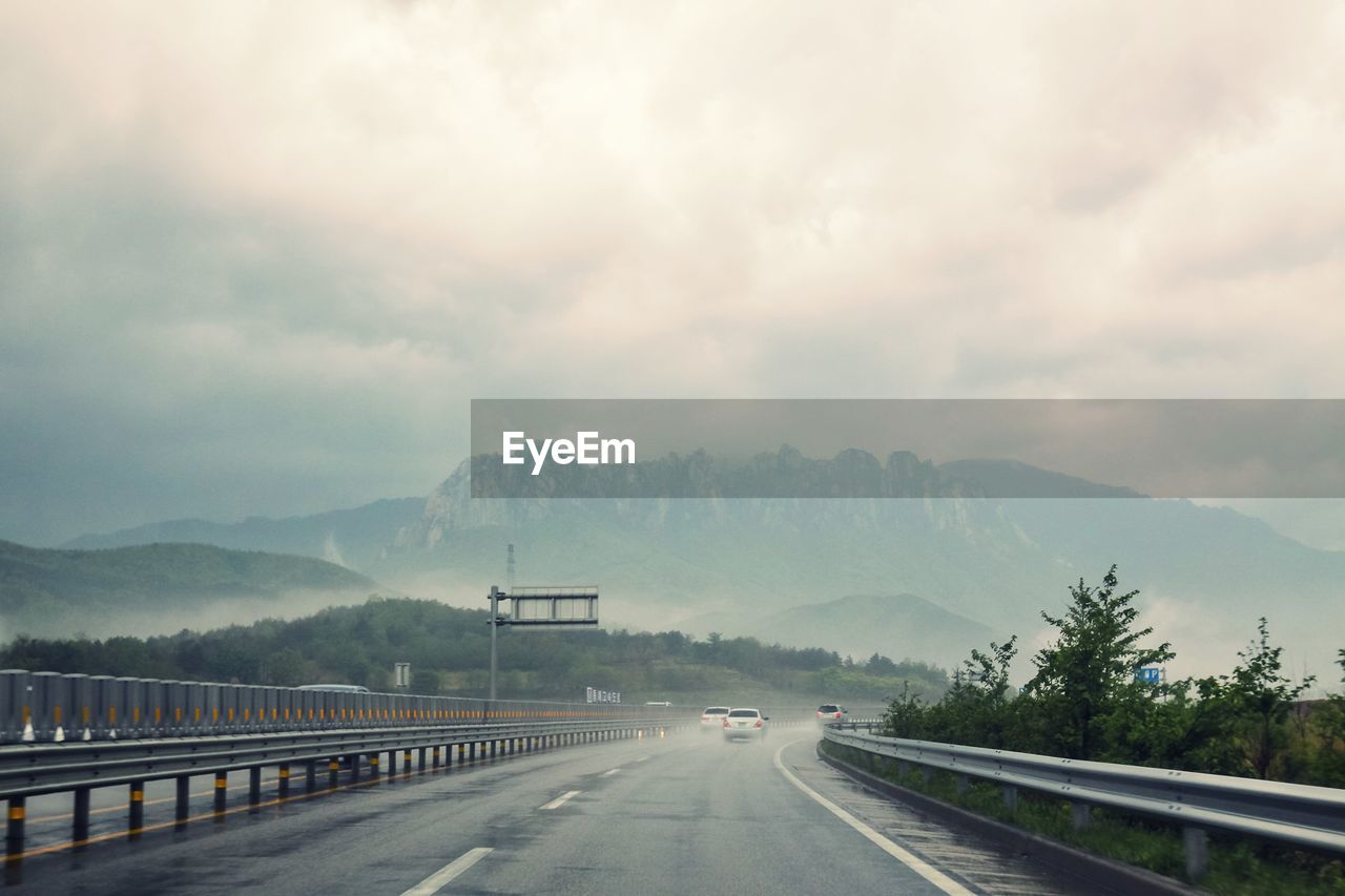 Road by mountains against sky