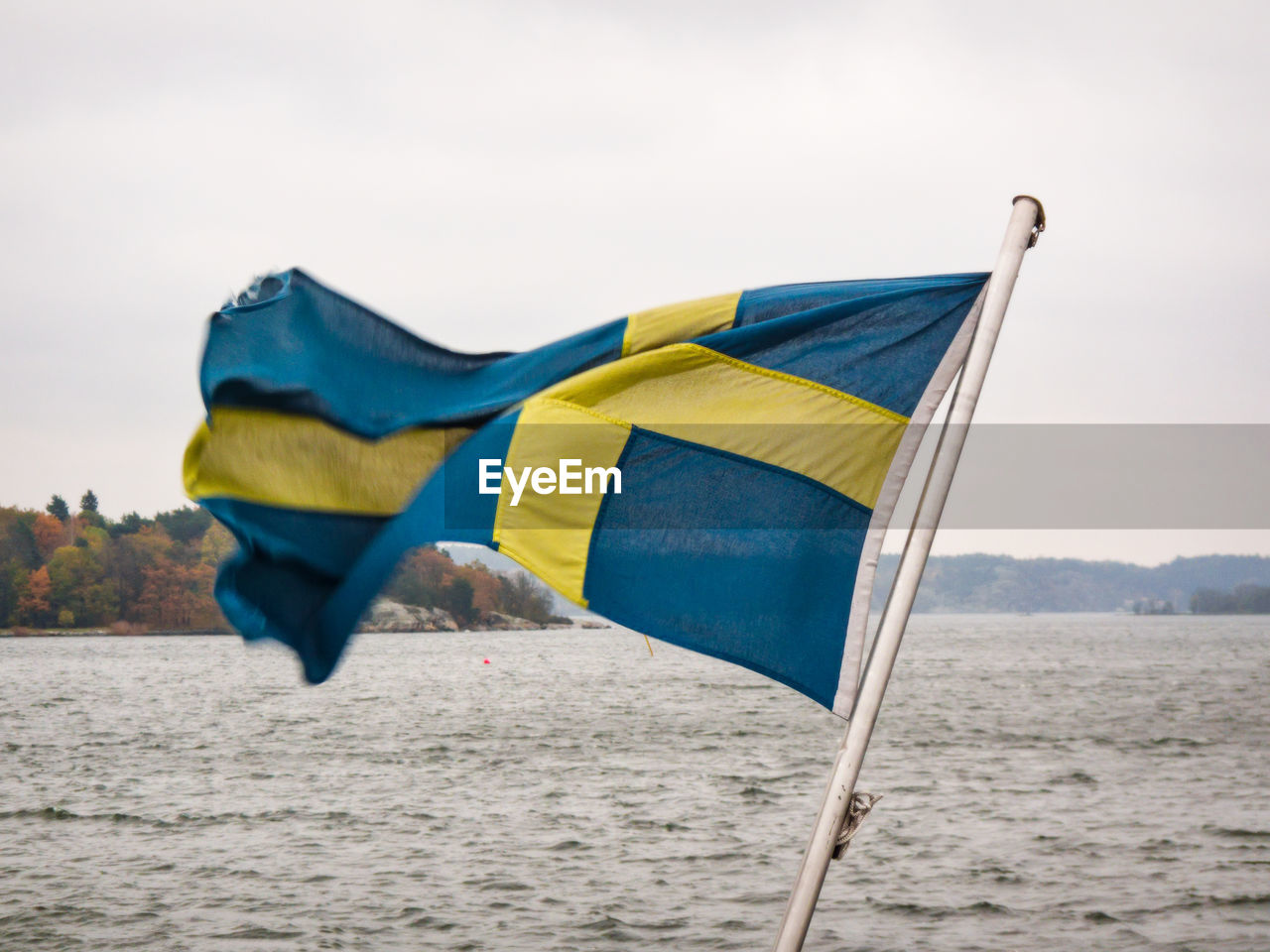 Swedish flag on pole against sea