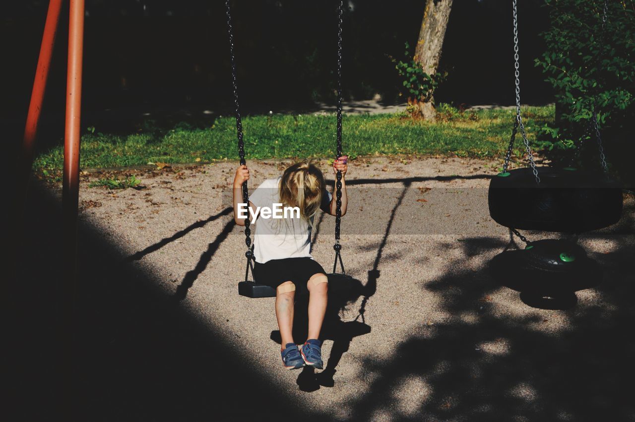 Full length of girl sitting on swing at playground