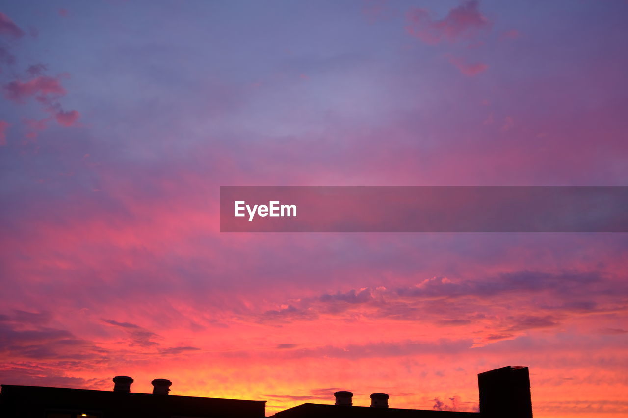 SILHOUETTE BUILDINGS AGAINST DRAMATIC SKY DURING SUNSET