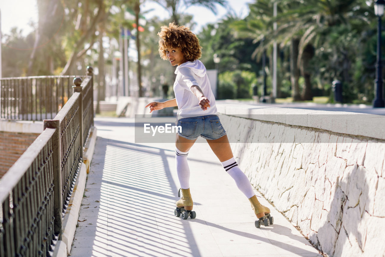 Full length portrait of young woman roller skating on bridge