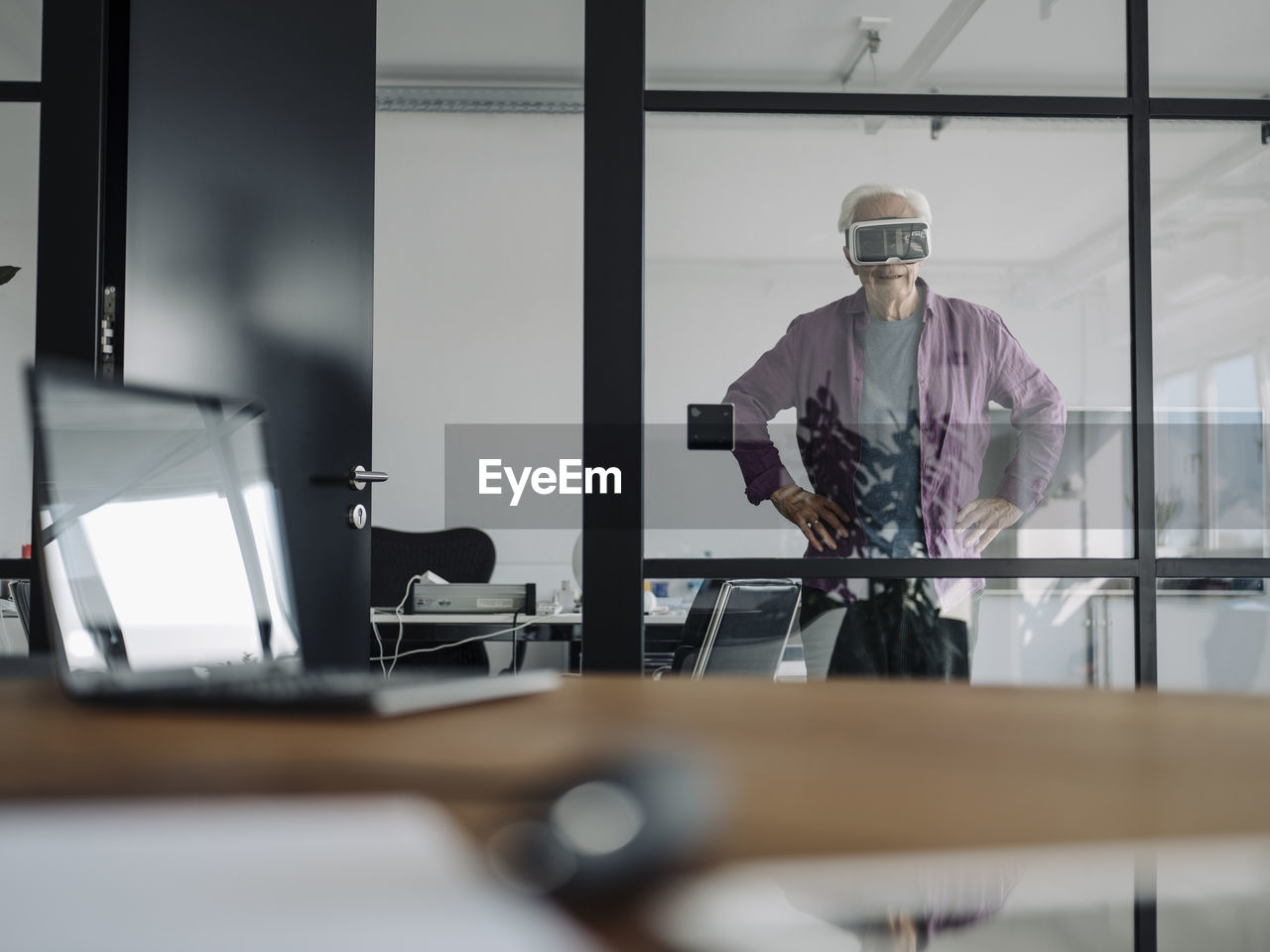 Senior businessman using virtual reality headset while standing in office