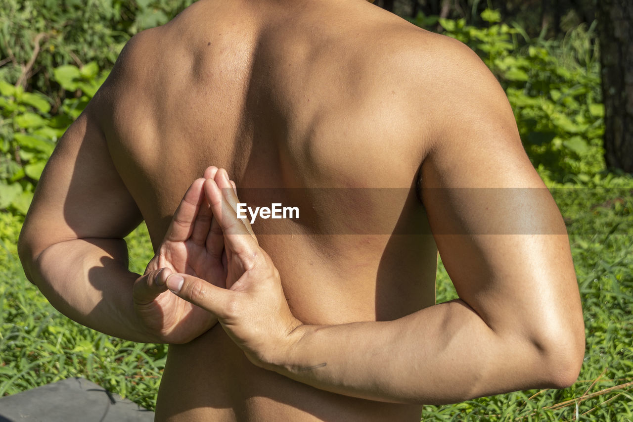 Latin american man doing yoga posture, yoga posture, bee backwards prsthatah brahmara, forest