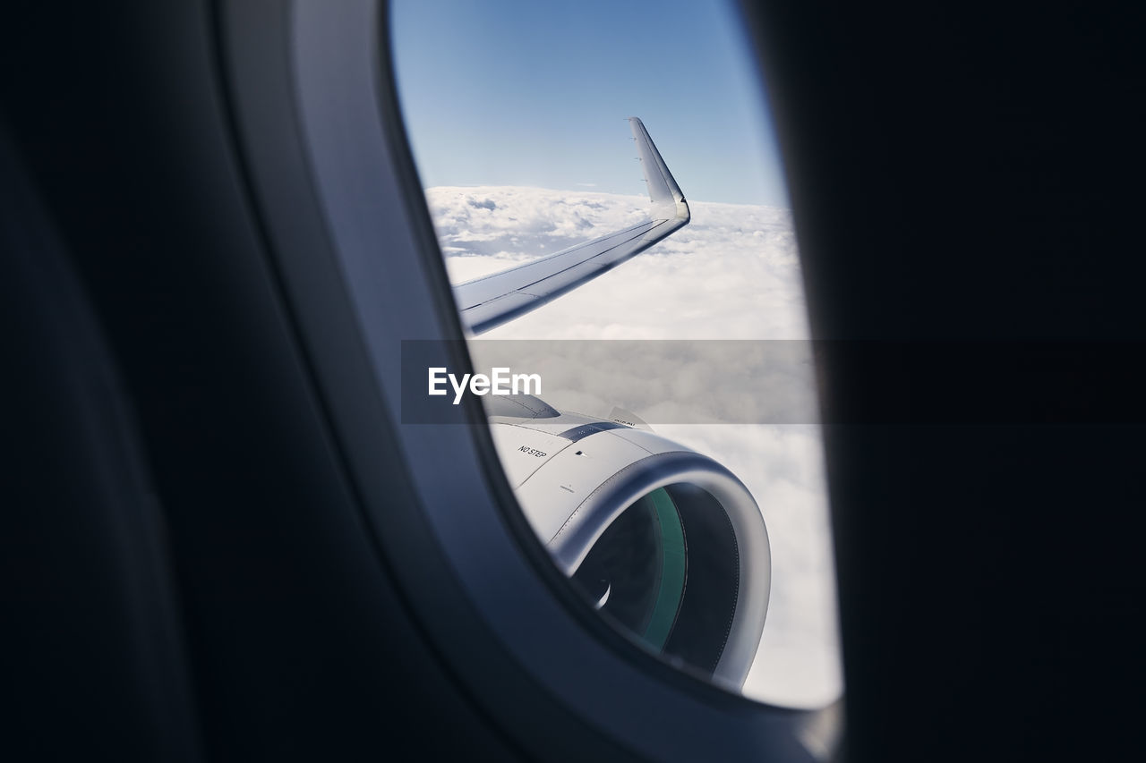 View through airplane window on wing with engine. plane during flight above clouds.