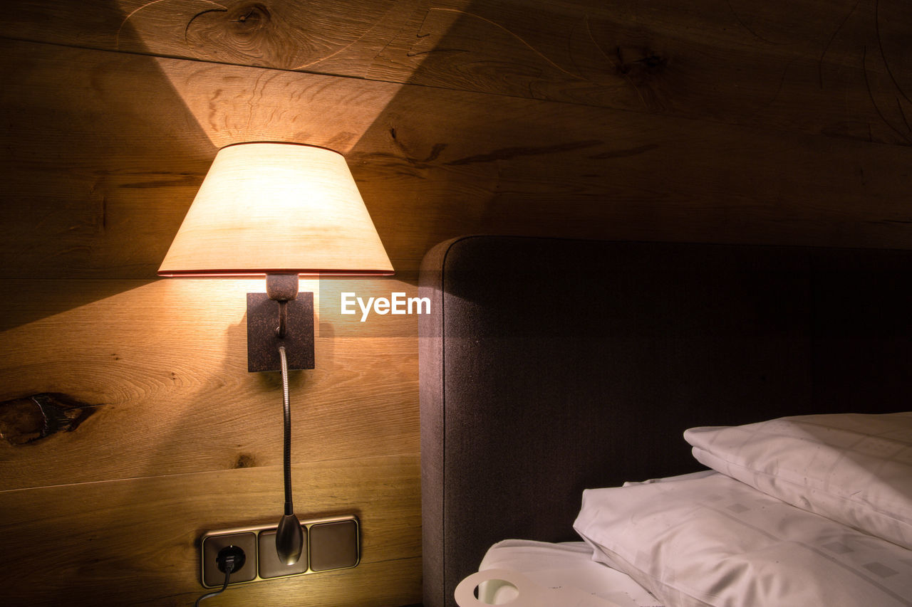 Illuminated floor lamp next to bed