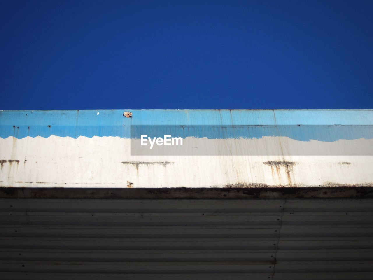 Low angle view of old garage against clear blue sky