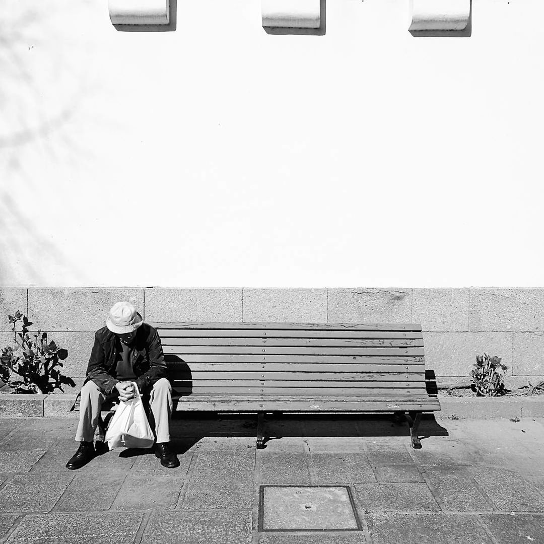 REAR VIEW OF TWO PEOPLE SITTING ON BENCH