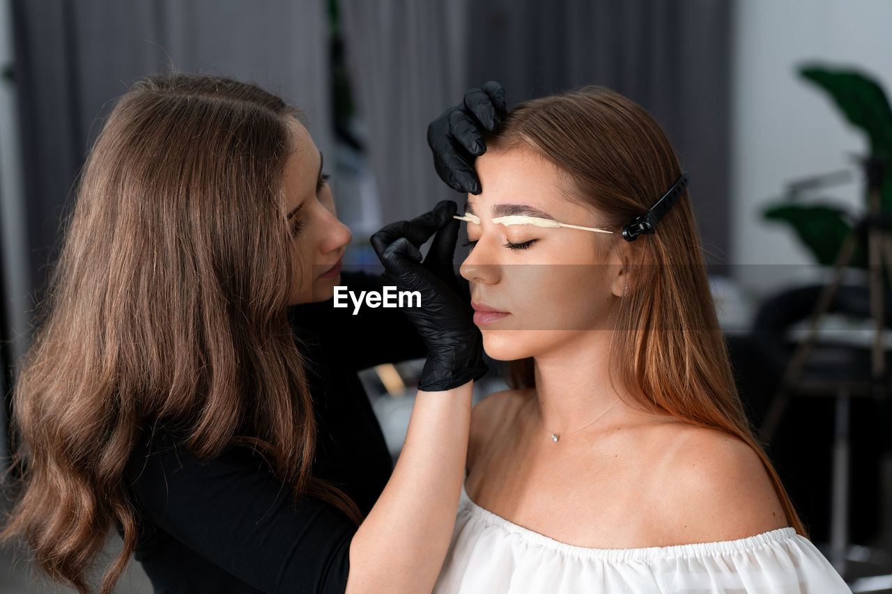 Close-up of of woman applying make-up to customer