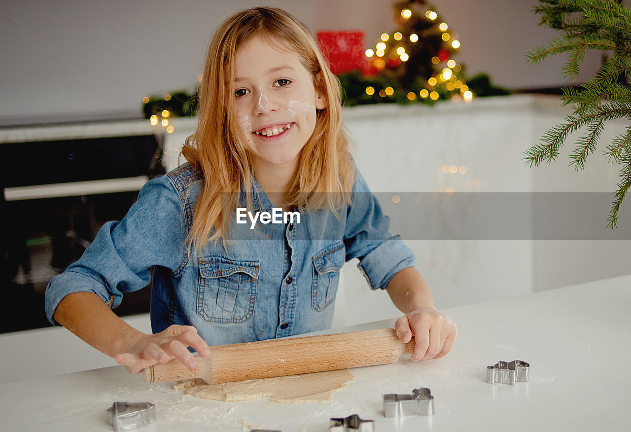 Happy little girl cooks christmas cookies at home in the kitchen . small blonde is preparing cookies 