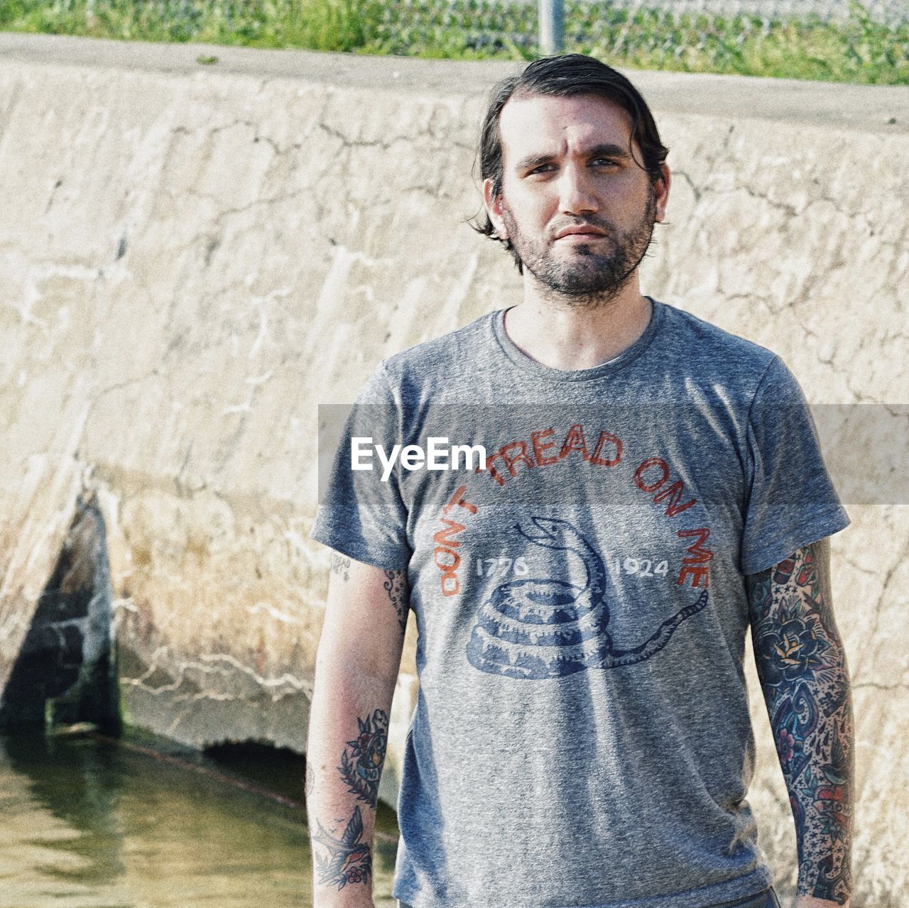 PORTRAIT OF MAN STANDING AGAINST WALL OUTDOORS