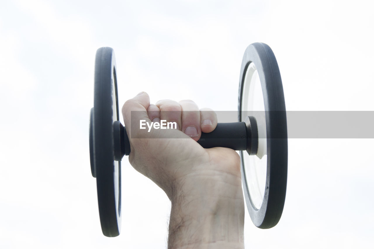Cropped image of hand holding weights against white background