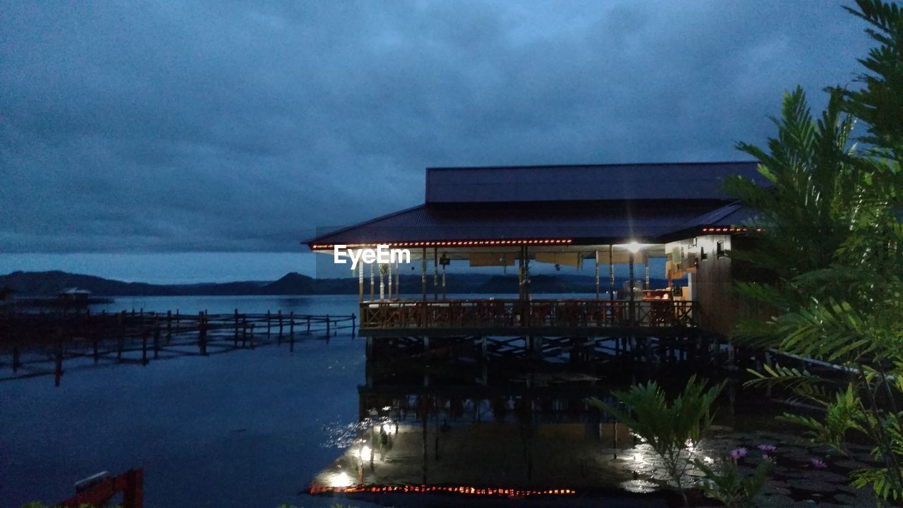 ILLUMINATED BUILDING BY SEA AGAINST SKY