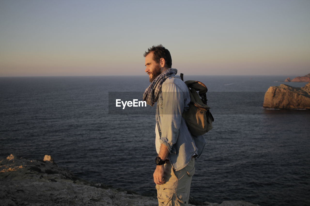 Side view of man standing against sea