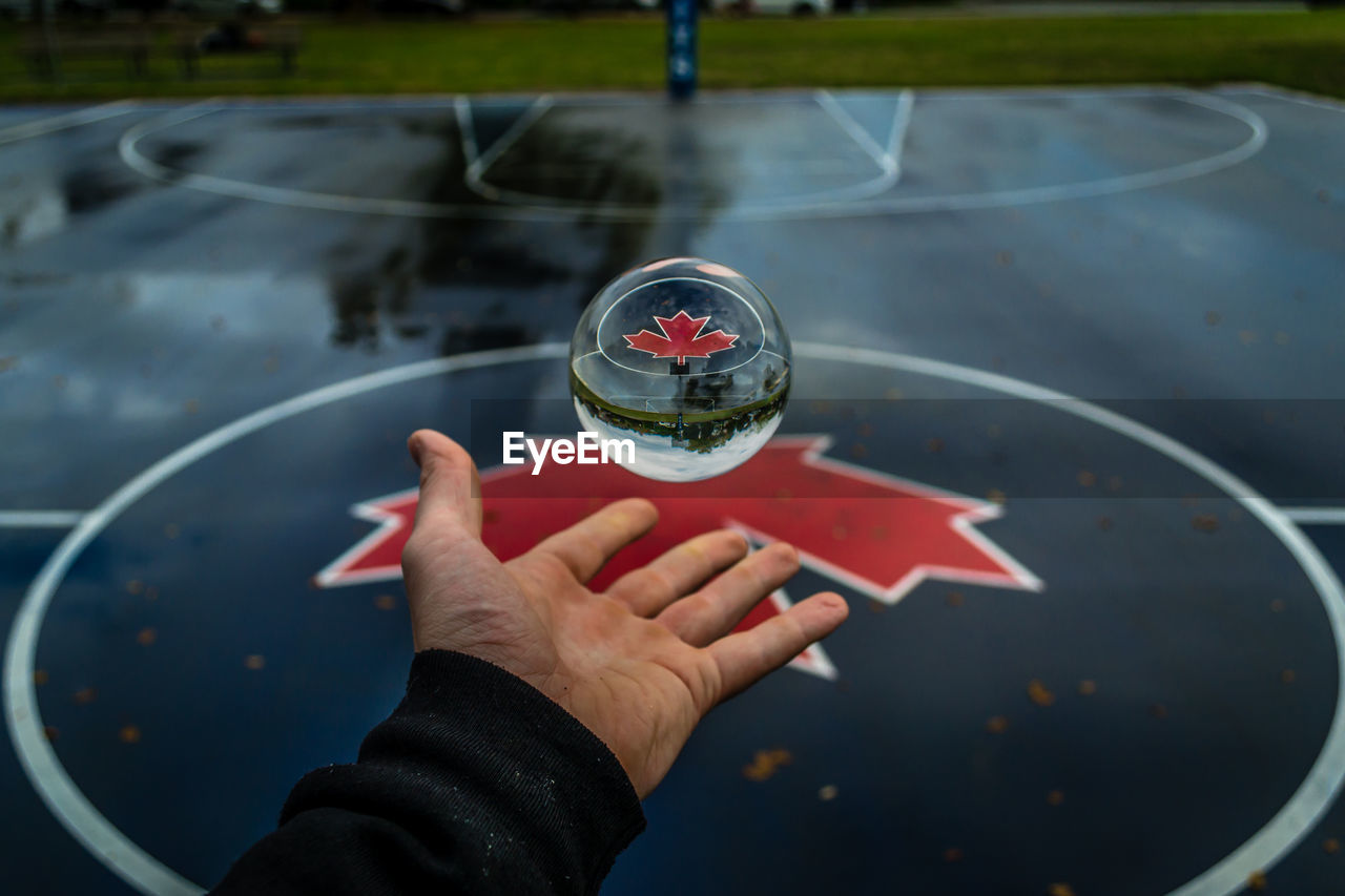 Cropped image of hand catching crystal ball in mid-air at basketball court