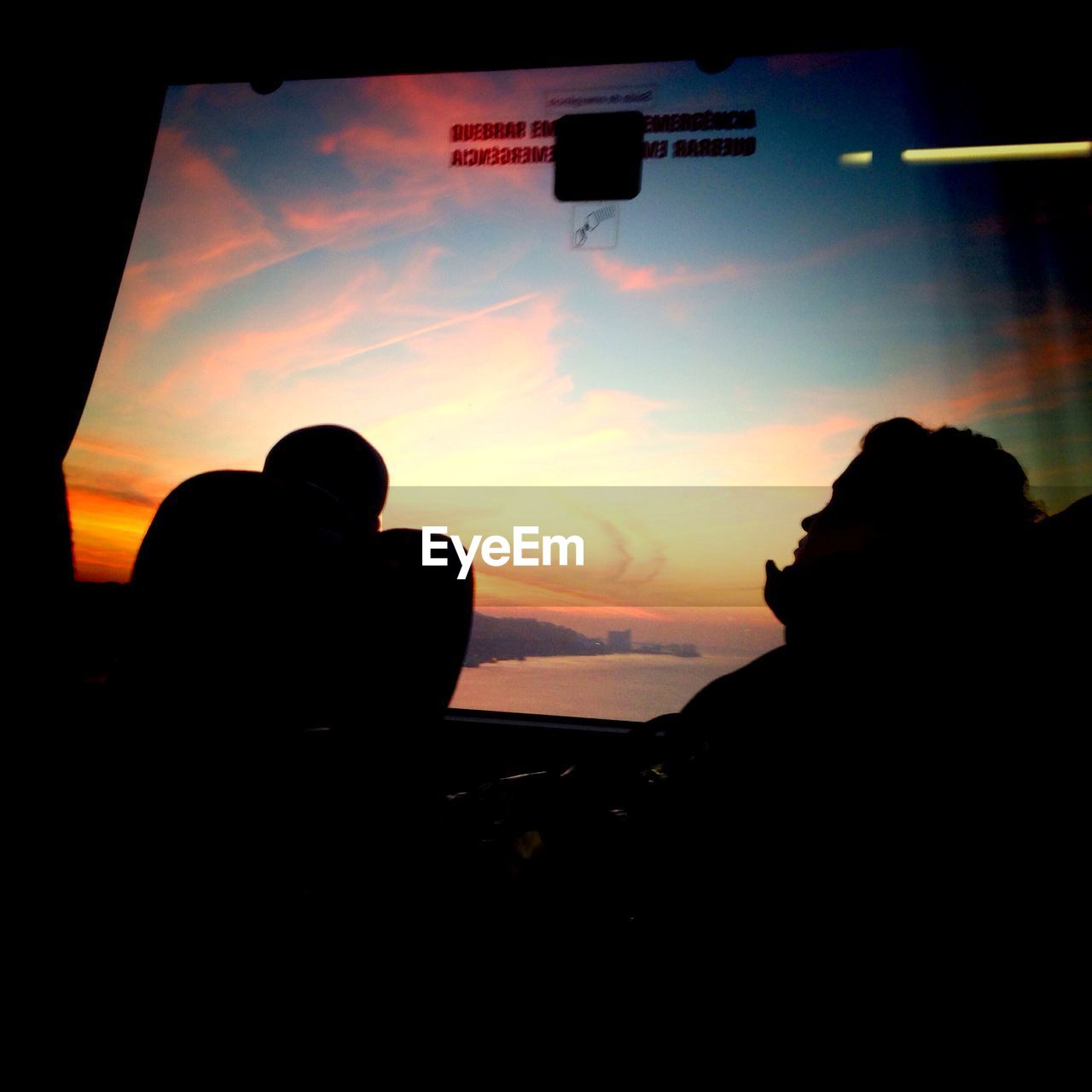 Silhouette people traveling in bus during sunset