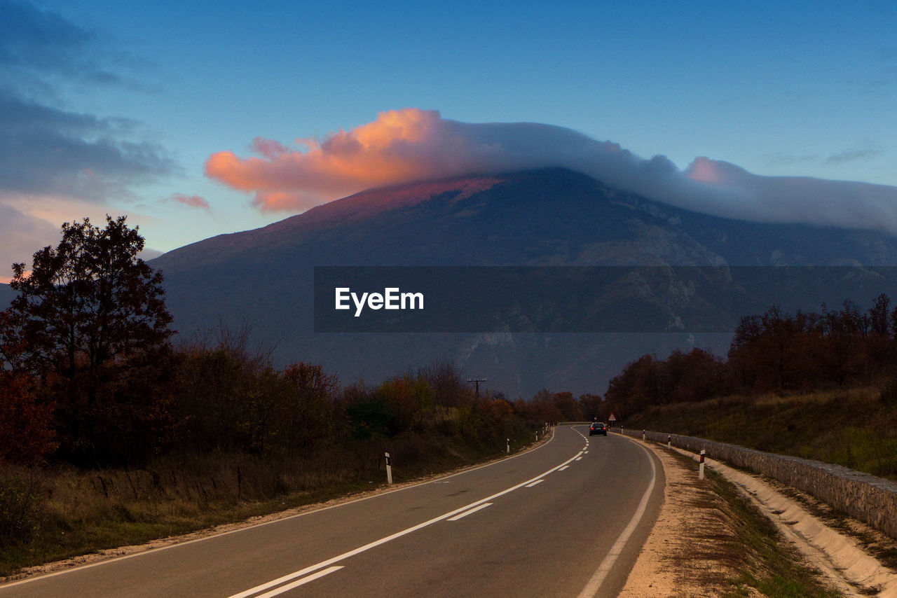 EMPTY ROAD AGAINST MOUNTAINS AND SKY