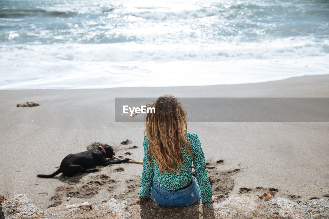 REAR VIEW OF WOMAN WITH DOG ON SHORE