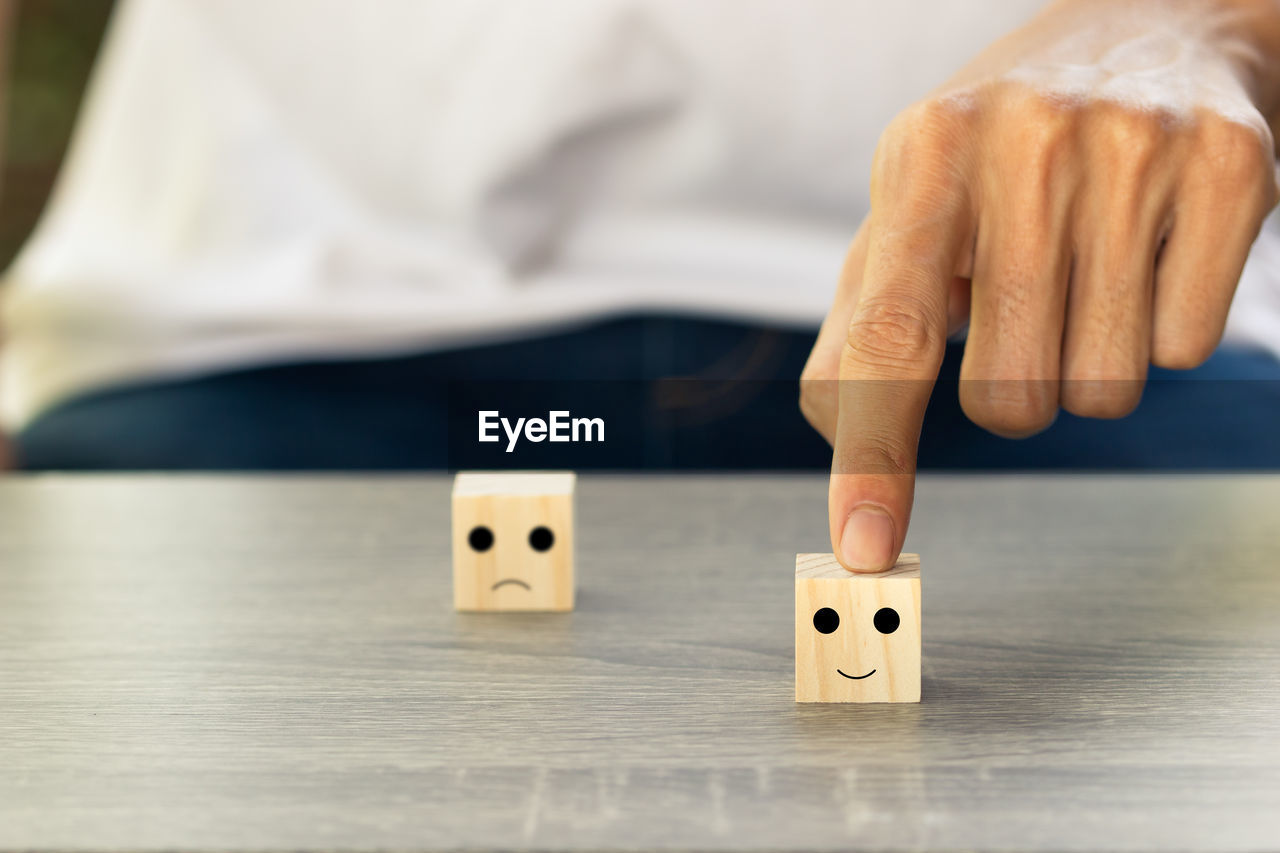 Midsection of person touching toy block on table