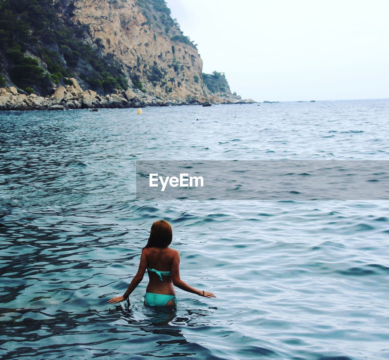 Rear view of young woman wearing bikini while standing in sea