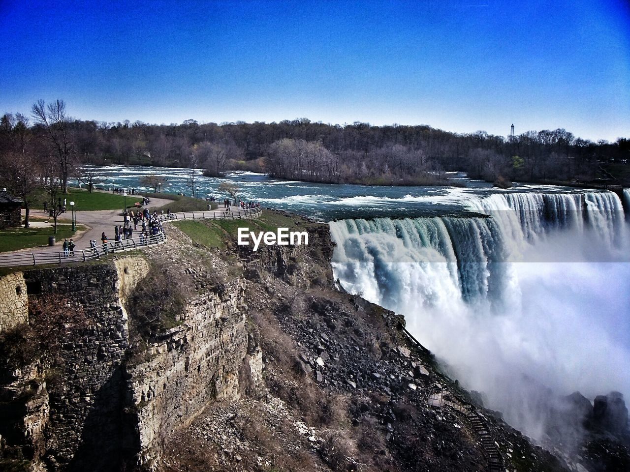 Scenic view of waterfall against clear blue sky