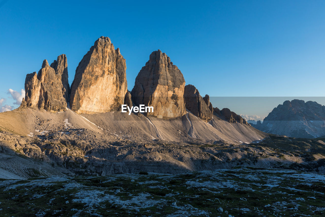 Panoramic view of rocky mountains against clear blue sky